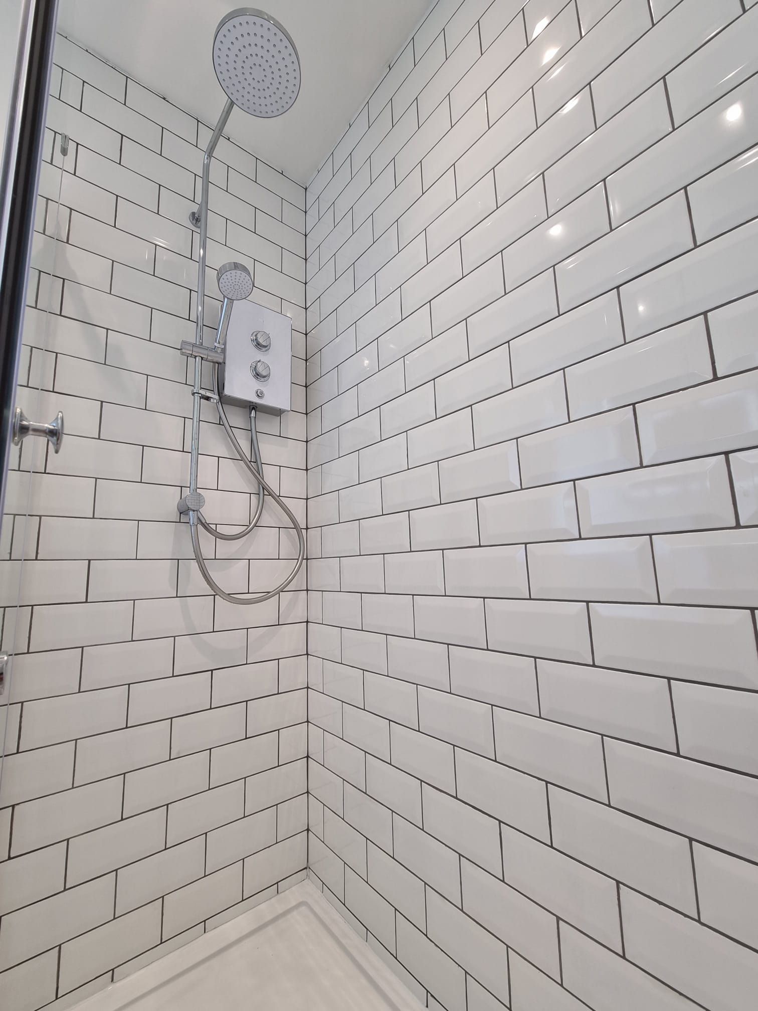 A shower with white brick walls and a shower head.