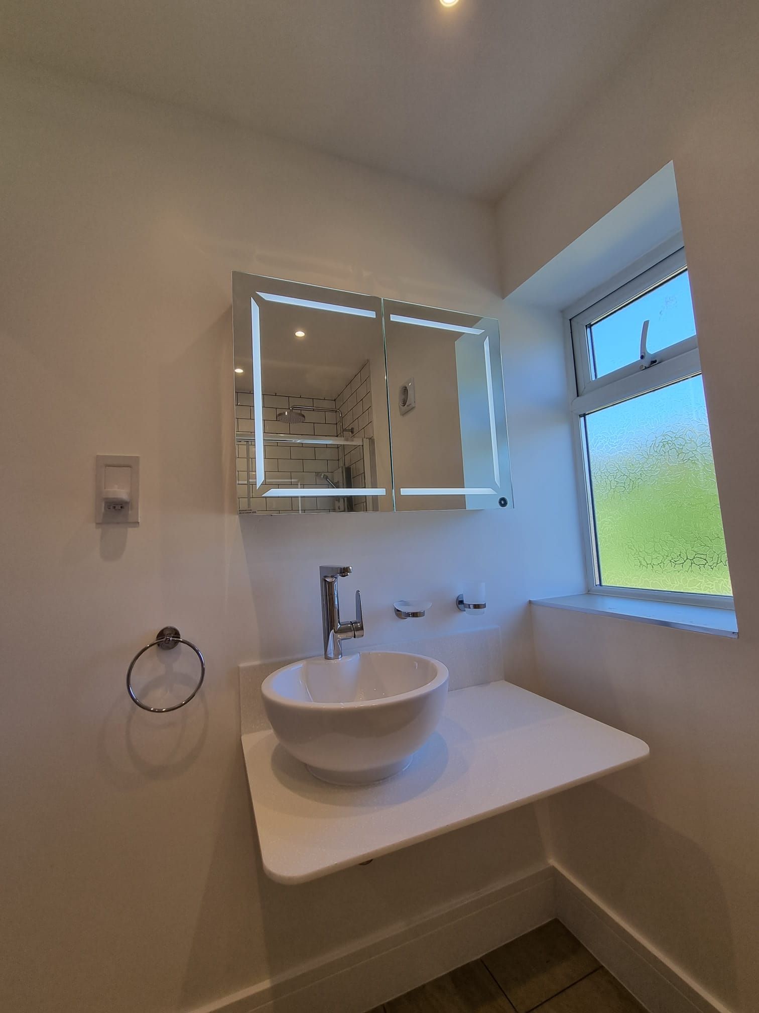 A bathroom with a sink , mirror and window