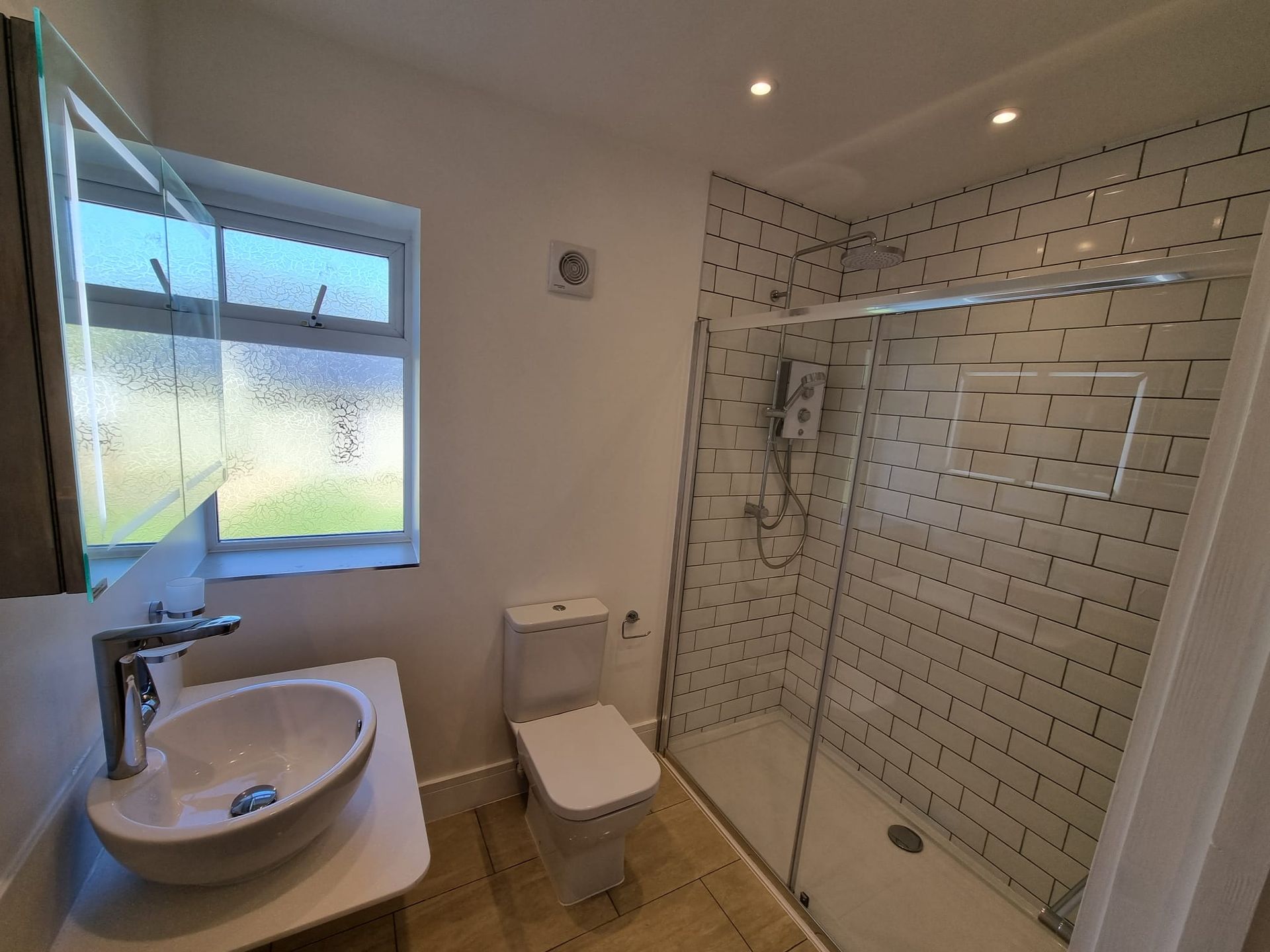 A bathroom with a toilet , sink and walk in shower.