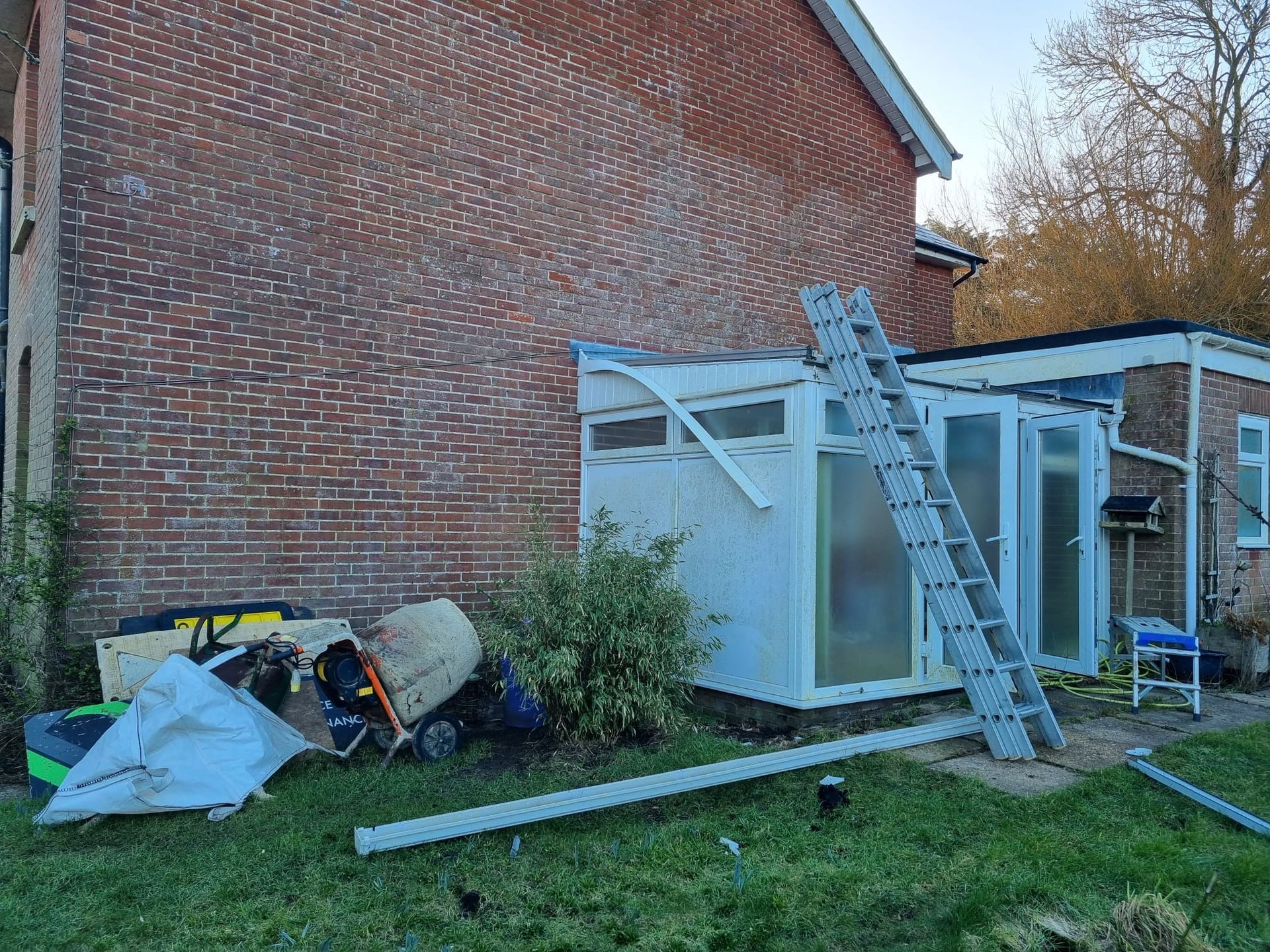 A ladder is sitting in front of a brick building.
