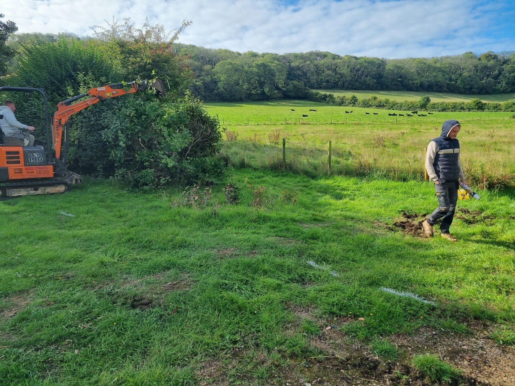 A man is walking in a field with a bulldozer in the background.