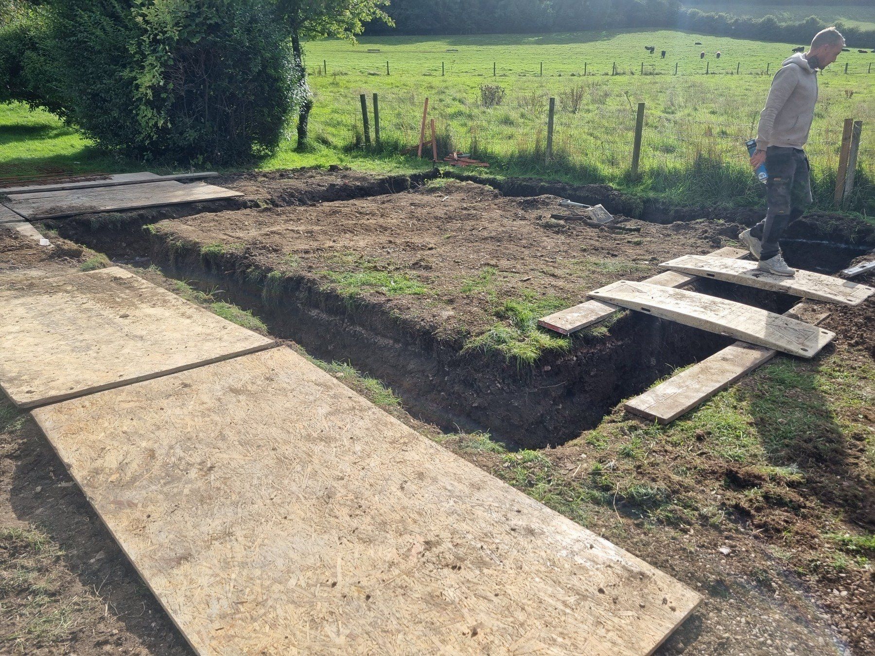 A man is digging a hole in the ground in a field.