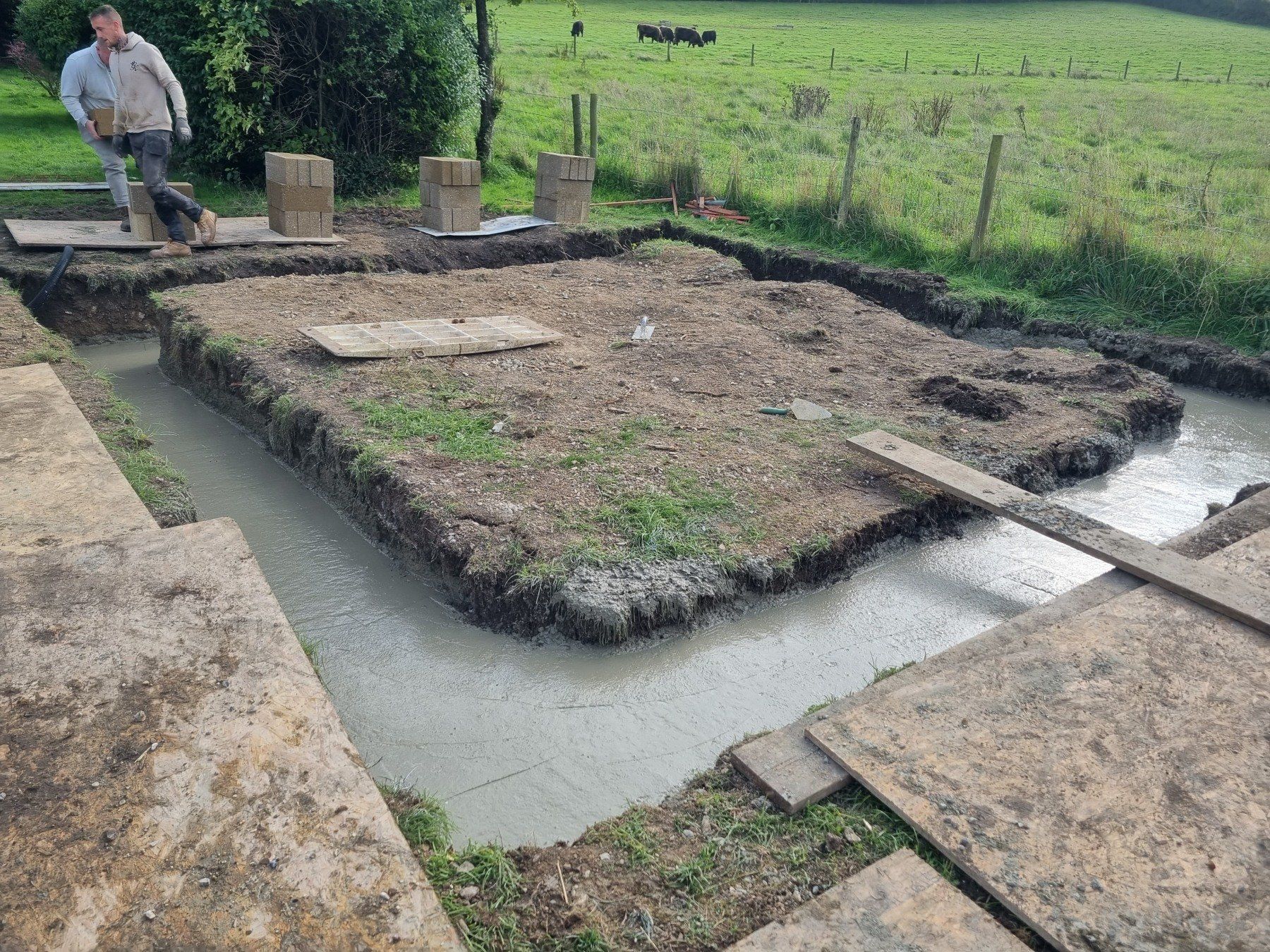 A man is pouring concrete into a hole in the ground.