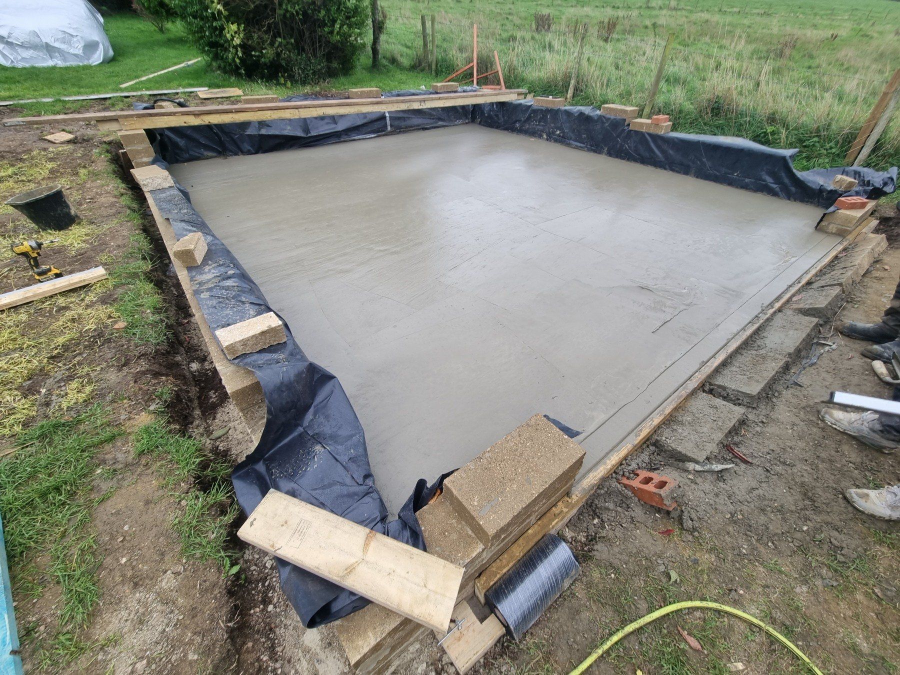 A concrete floor is being built in a yard.
