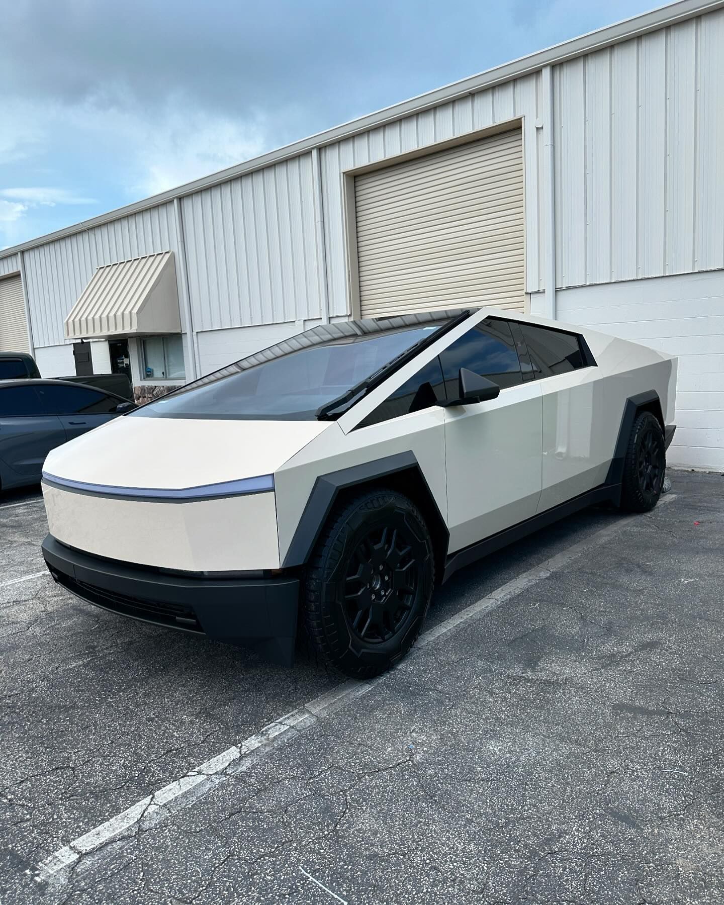 A white tesla cybertruck is parked in front of a building.