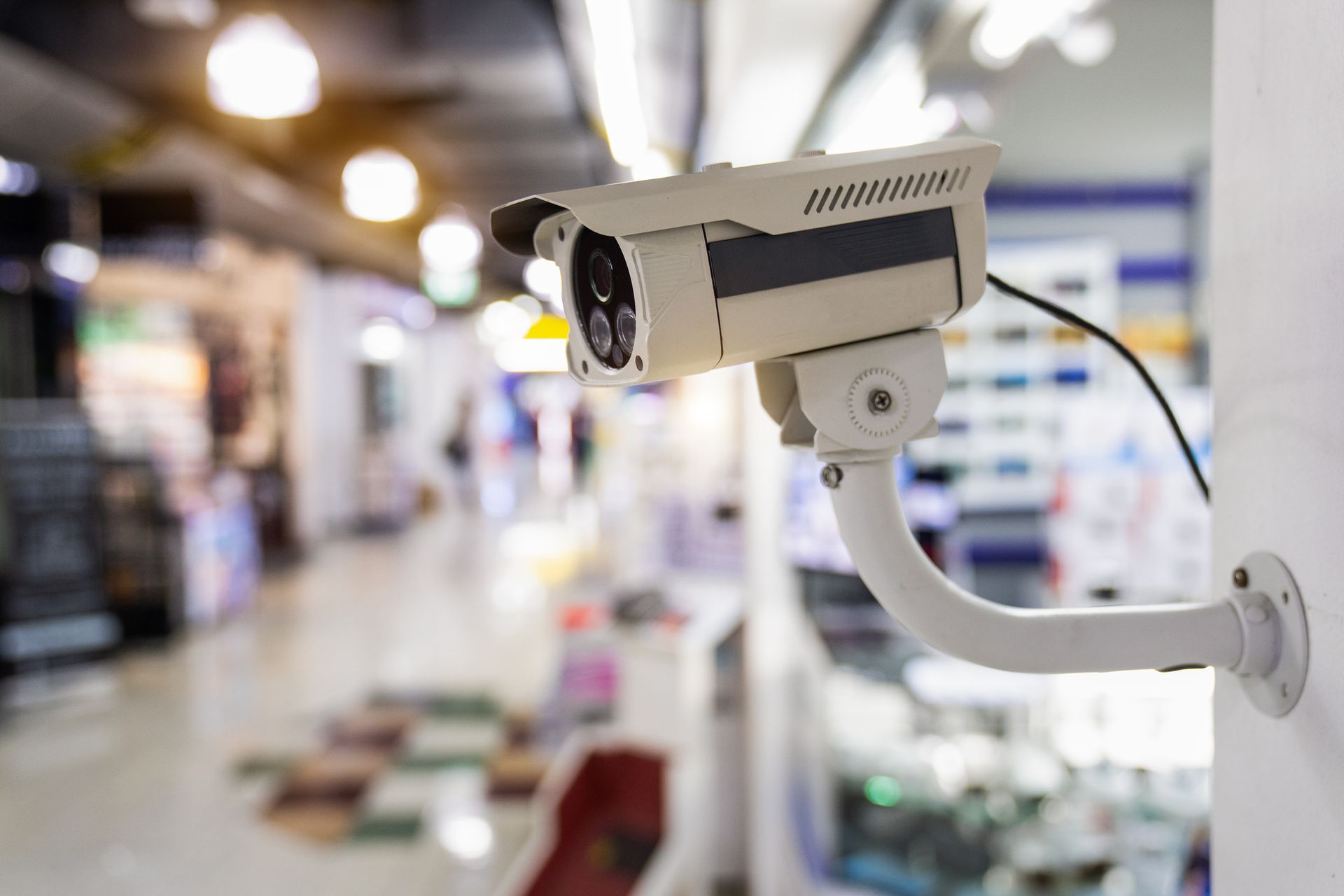 Security camera mounted on a wall inside a store, monitoring the shopping area.