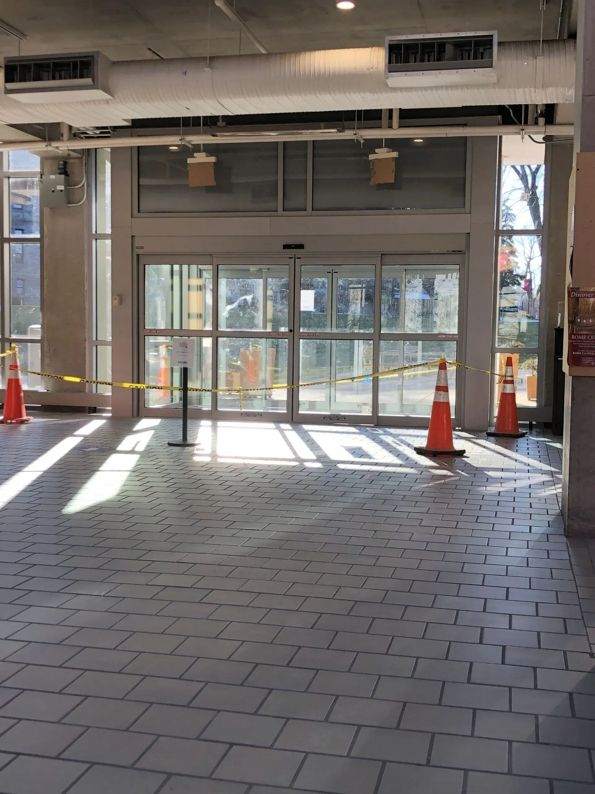 A building with a sliding glass door and orange cones in front of it