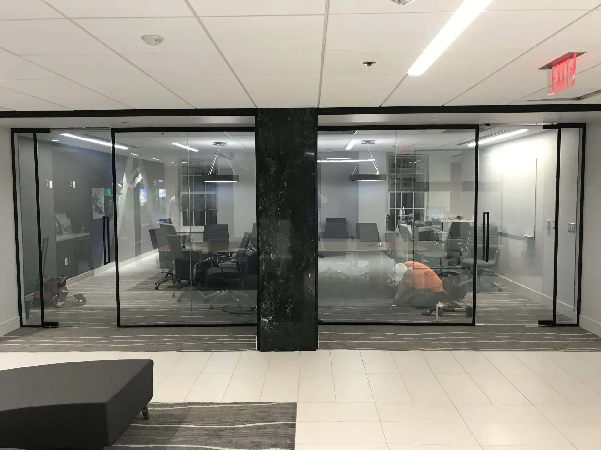 A conference room with sliding glass doors and a red exit sign.