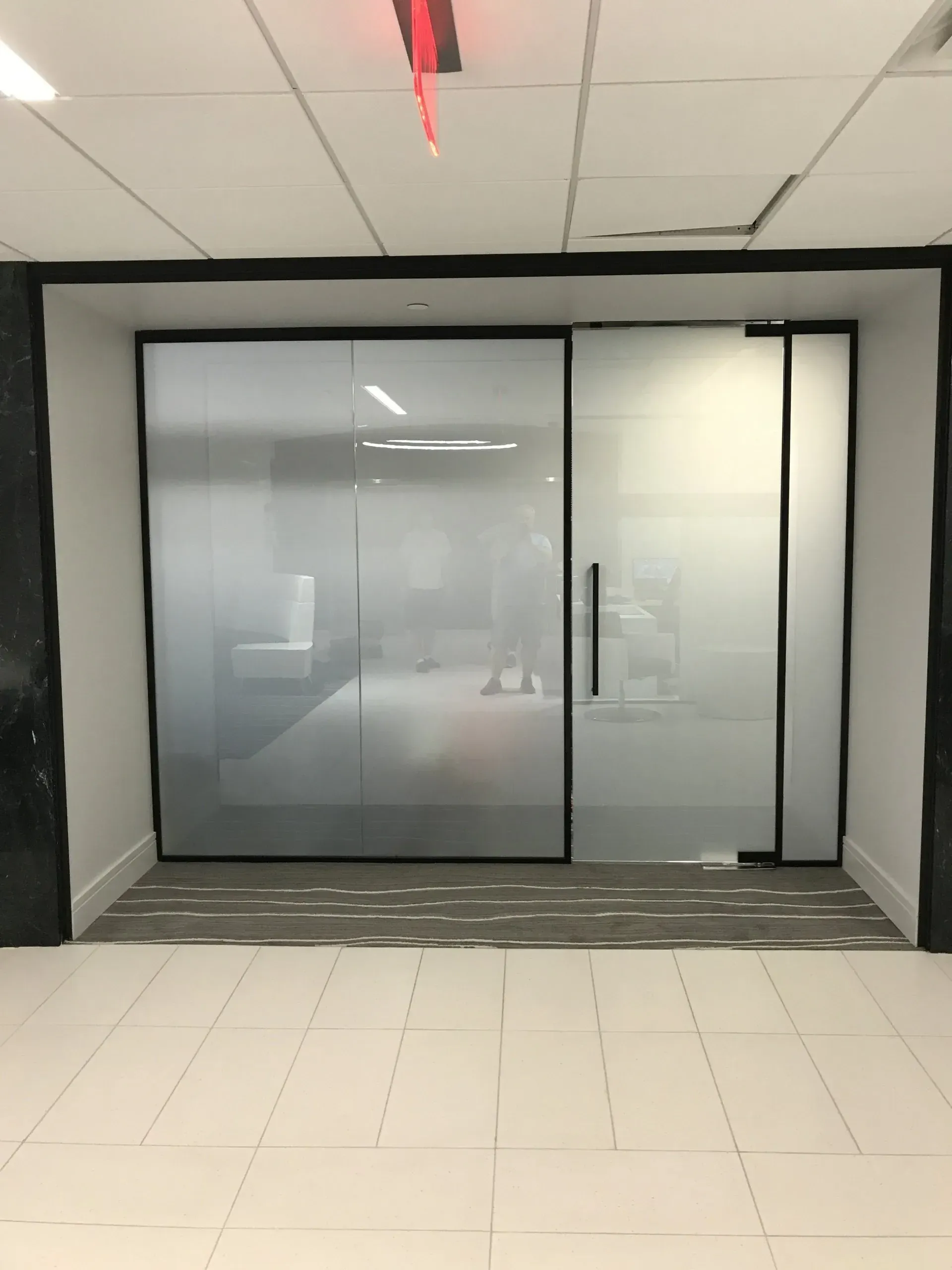 A room with a sliding glass door and a red light on the ceiling