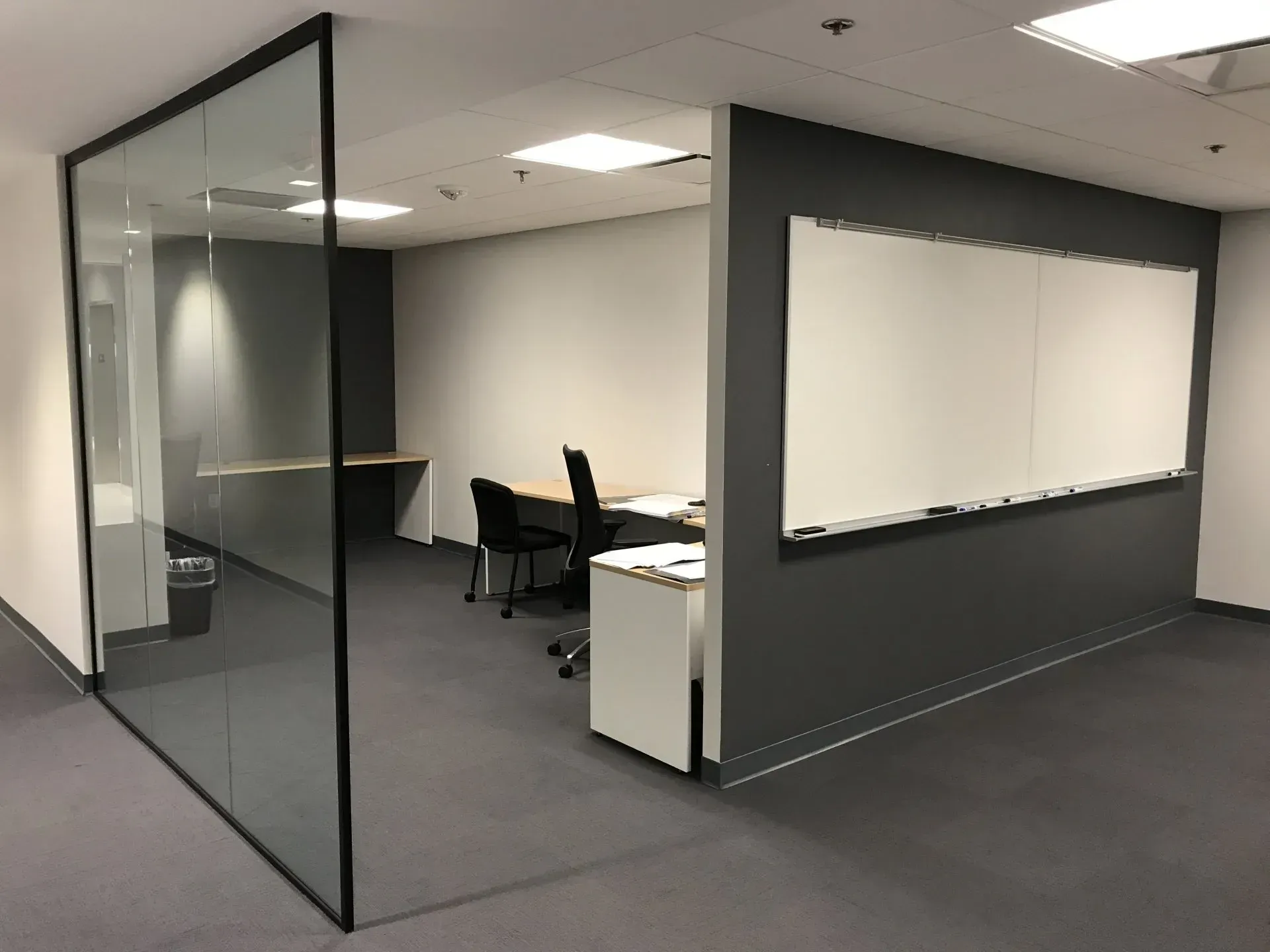 A room with a glass wall and a white board on the wall.