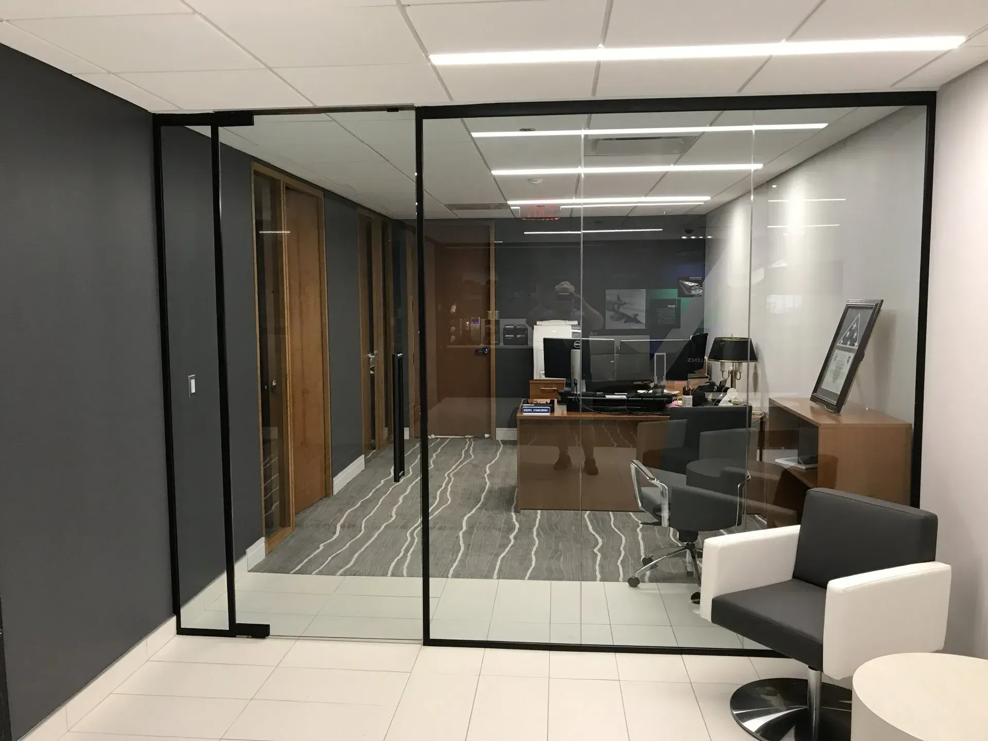 A room with a desk , chairs , and a glass wall.