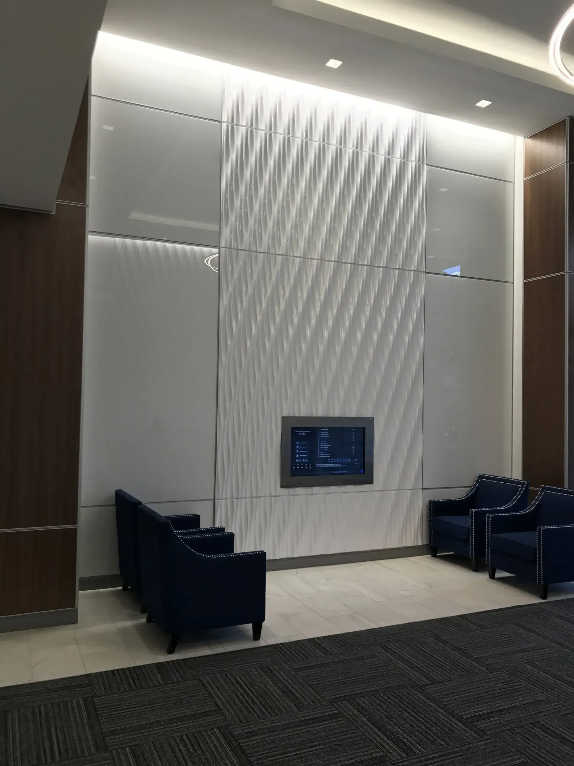 A waiting room with blue chairs and a television on the wall