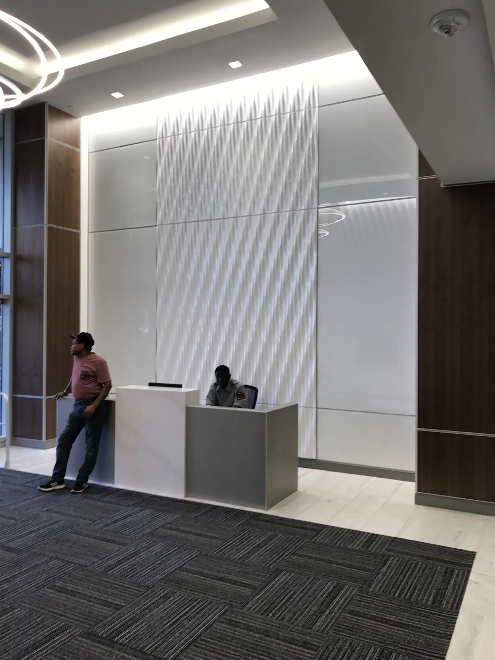 A man is sitting at a reception desk in a lobby.