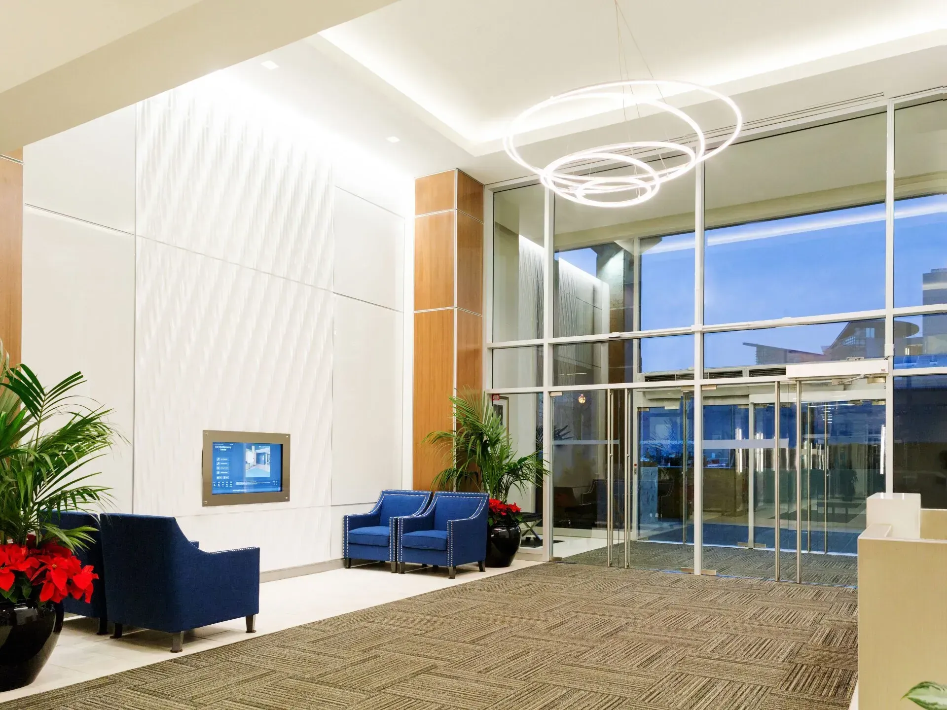 A lobby with blue chairs and a tv on the wall