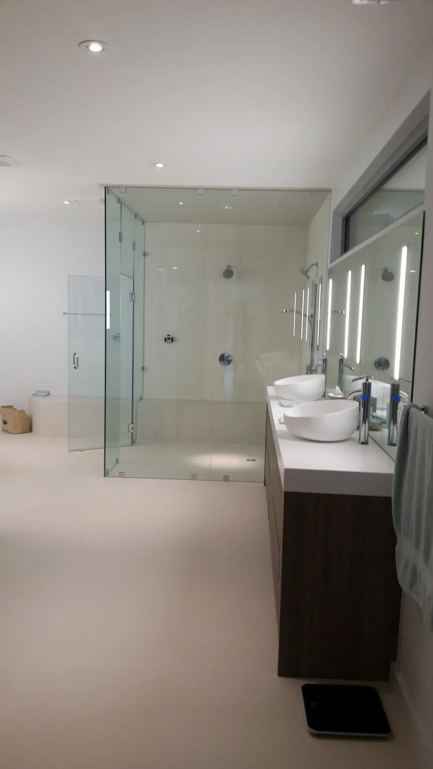 A bathroom with two sinks and a walk in shower.