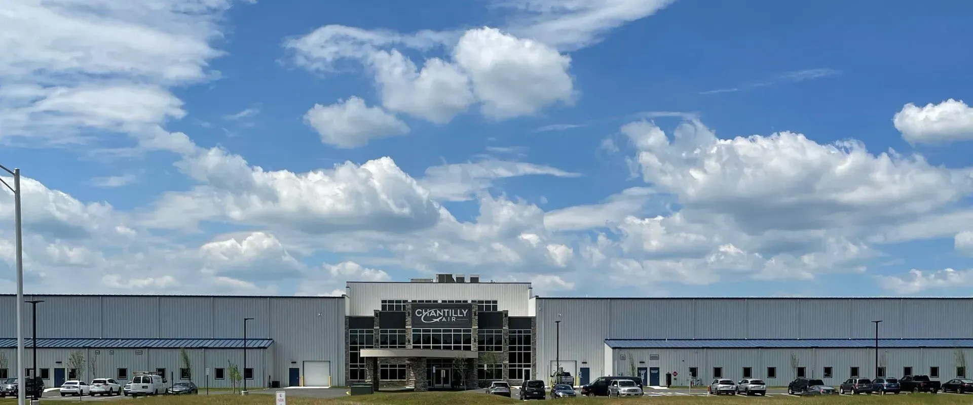 A large white building with a blue sky and clouds in the background.