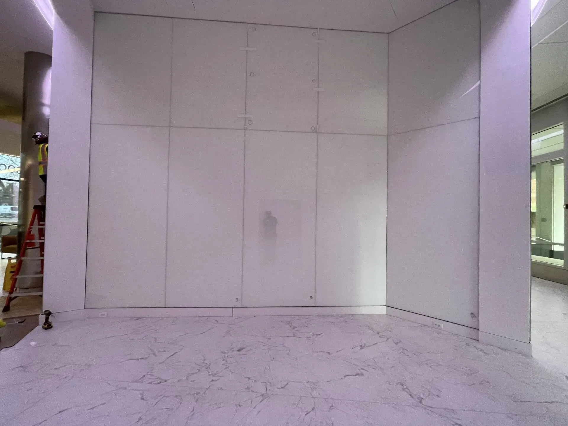 An empty room with white walls and a ladder in the corner.