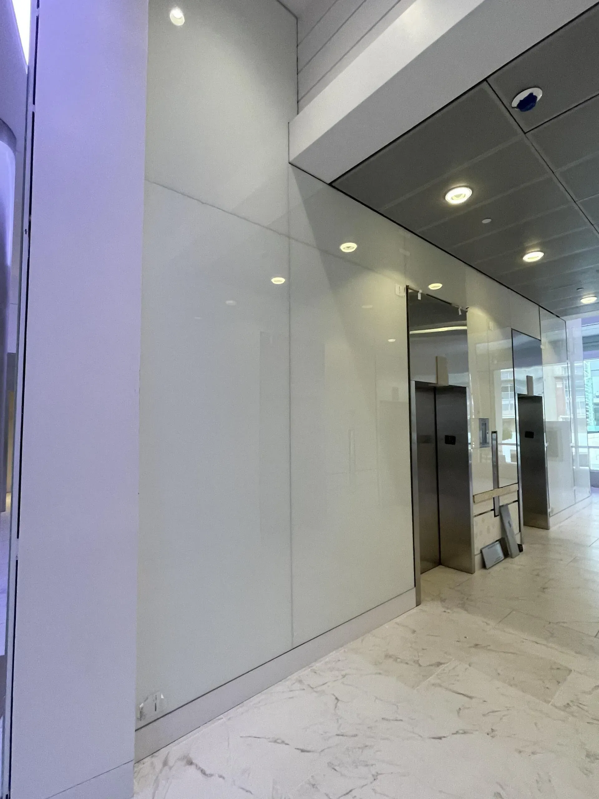 A hallway with elevators and a white wall