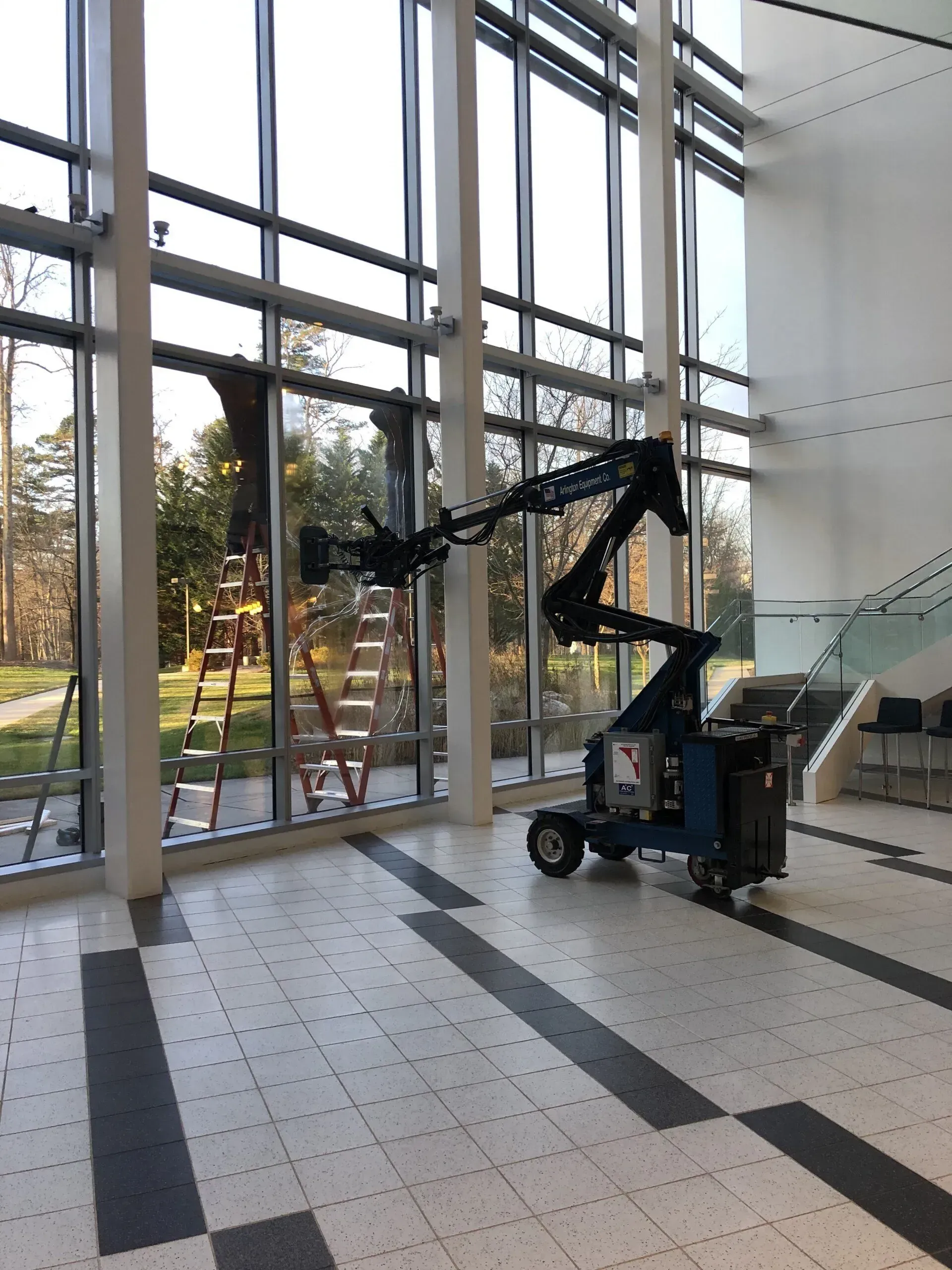 A man is standing on a ladder in front of a large window.