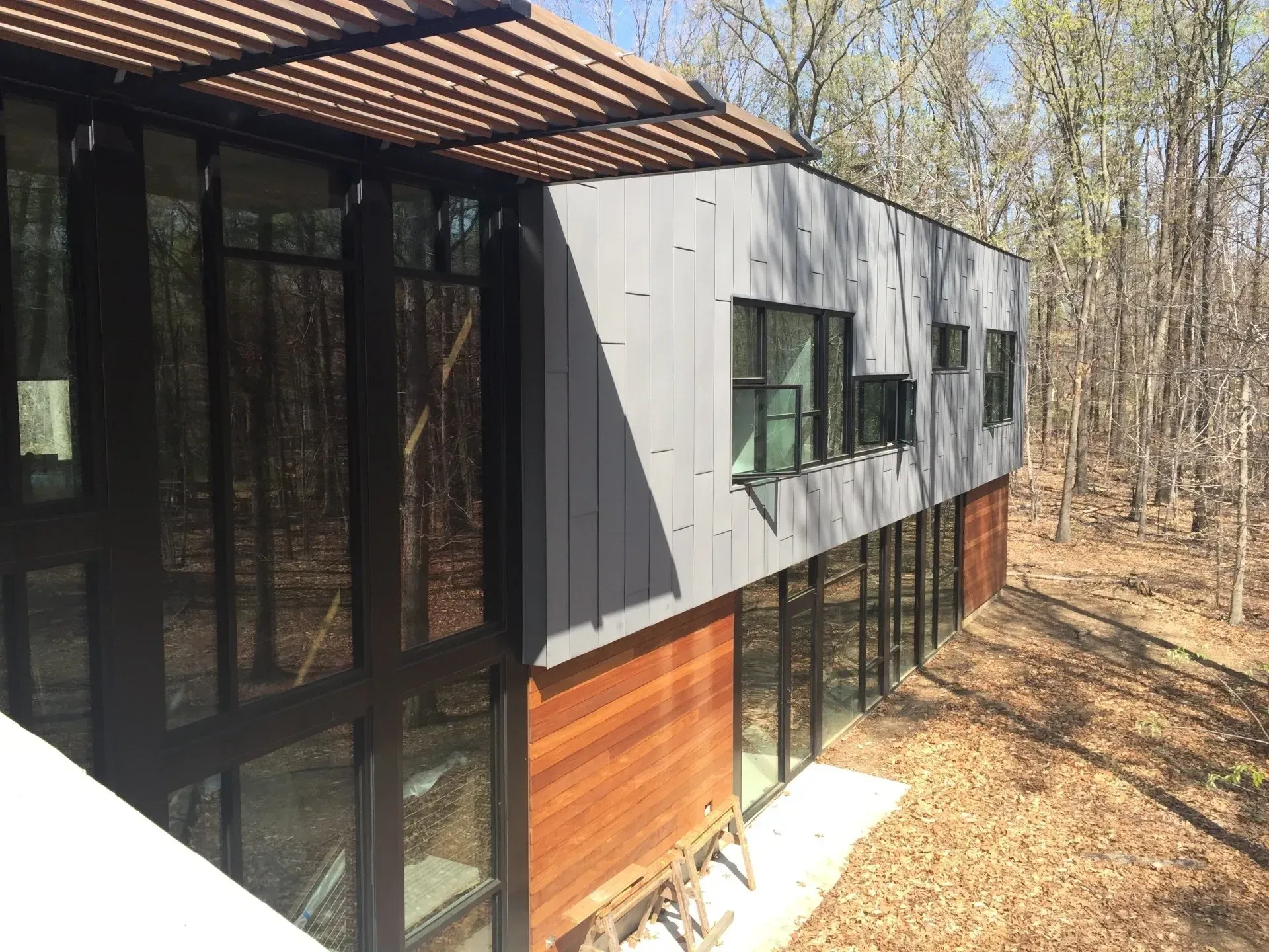 A modern house with a lot of windows is surrounded by trees.