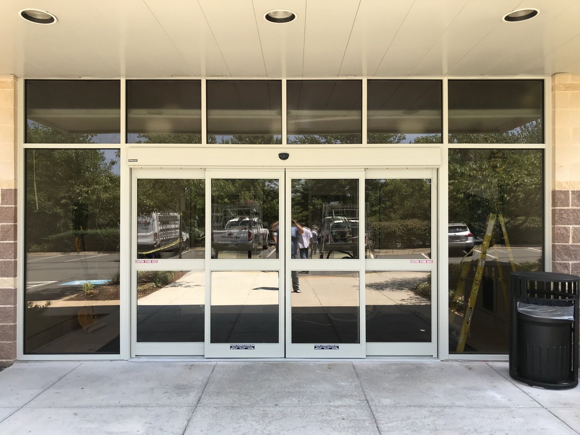 A large sliding glass door with a trash can in front of it.