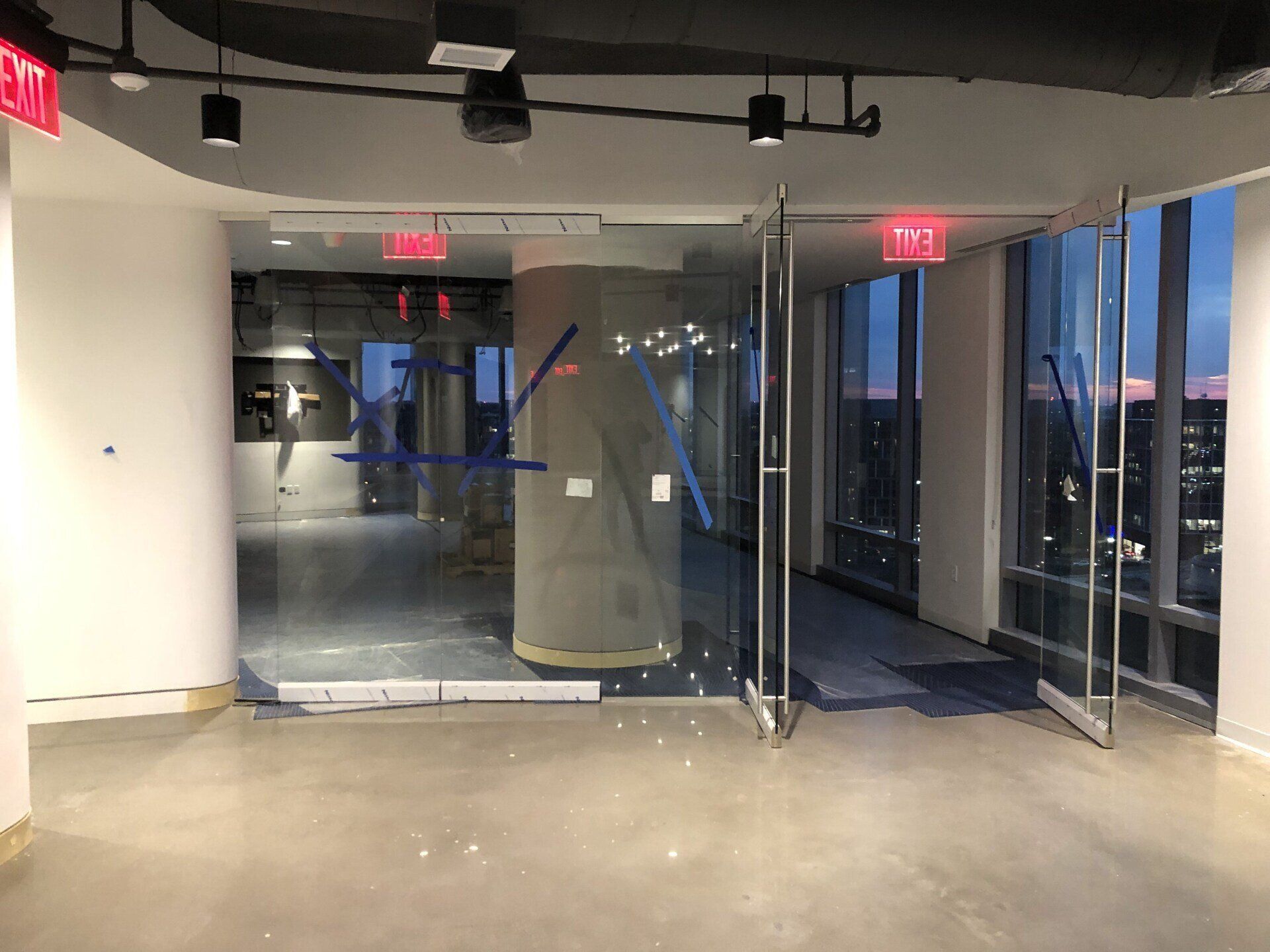 A large empty room with a red exit sign on the ceiling.