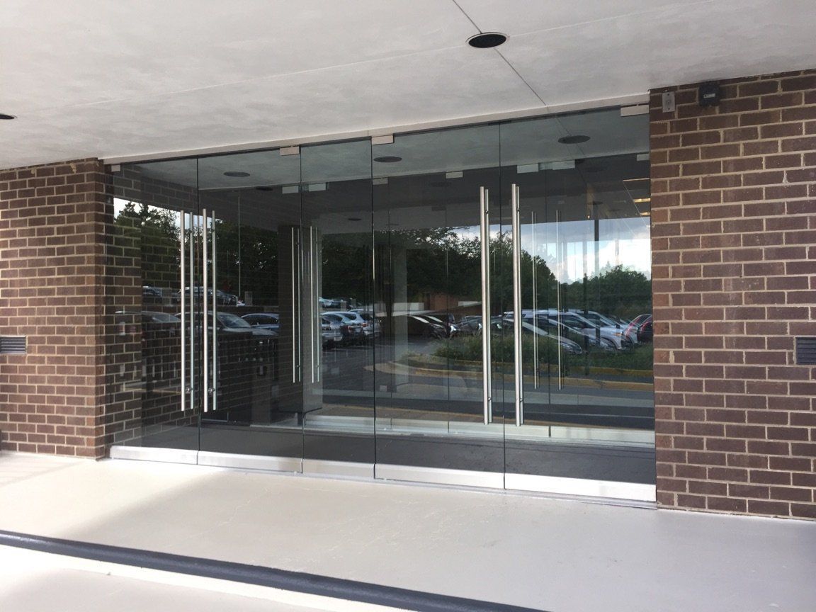 A brick building with a glass door and a lot of cars parked in front of it.