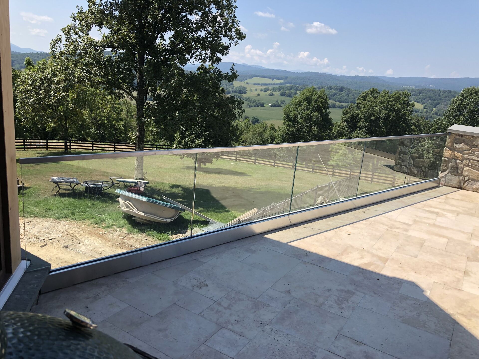 A balcony with a glass railing overlooking a lush green field.