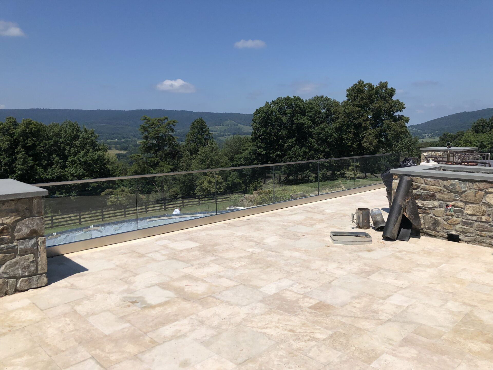 A patio with a glass railing and trees in the background.