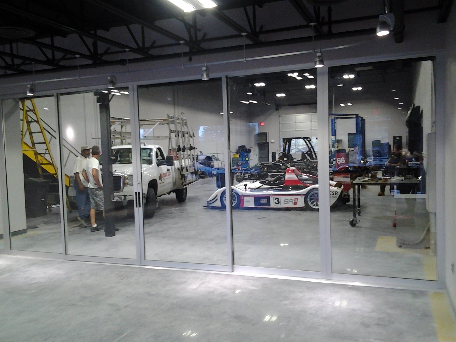 A white truck is parked in a garage next to a go kart