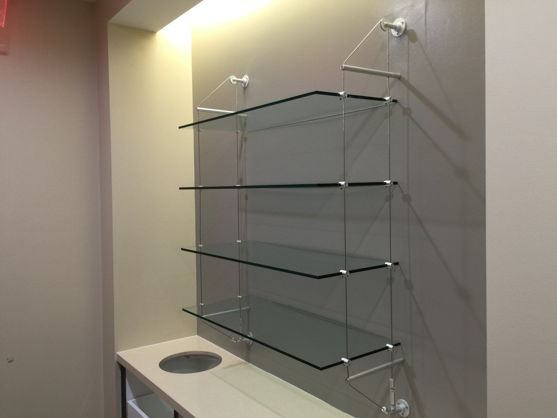 A glass shelf is hanging on a wall next to a counter.