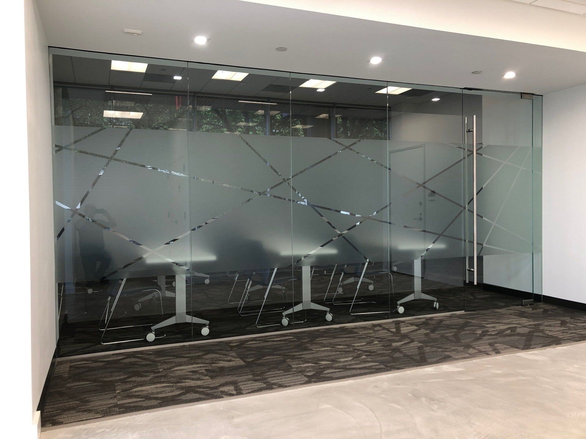 A conference room with a glass wall and tables in it.