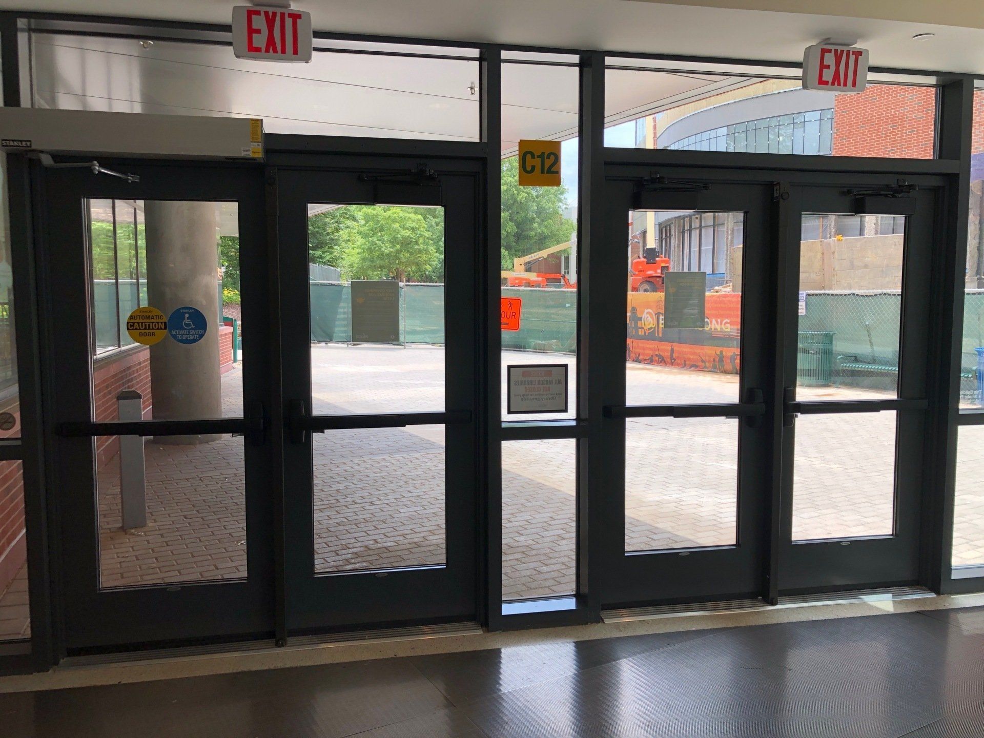 A hallway with a lot of doors and a red exit sign.