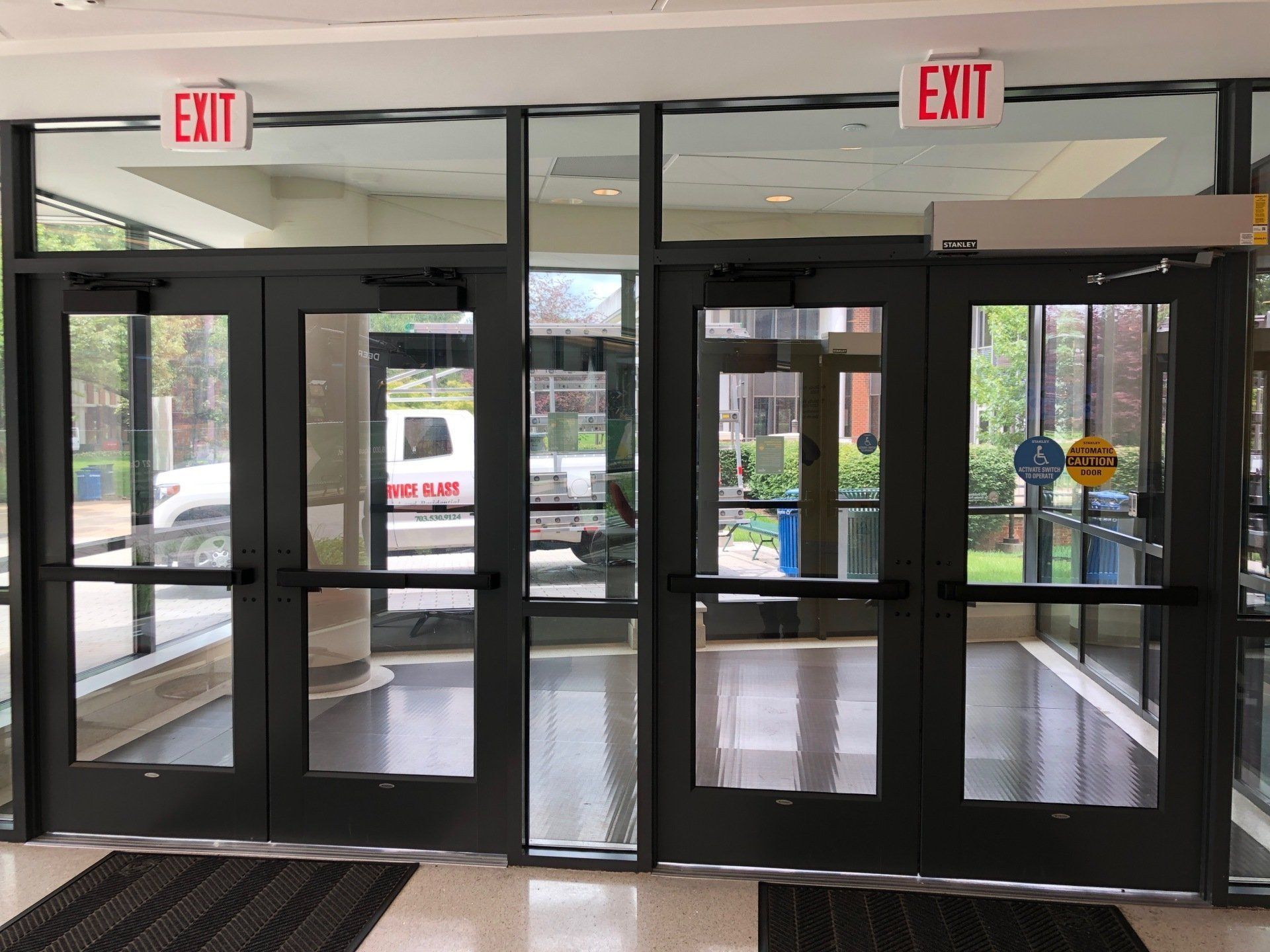 A hallway with a red exit sign above the doors.