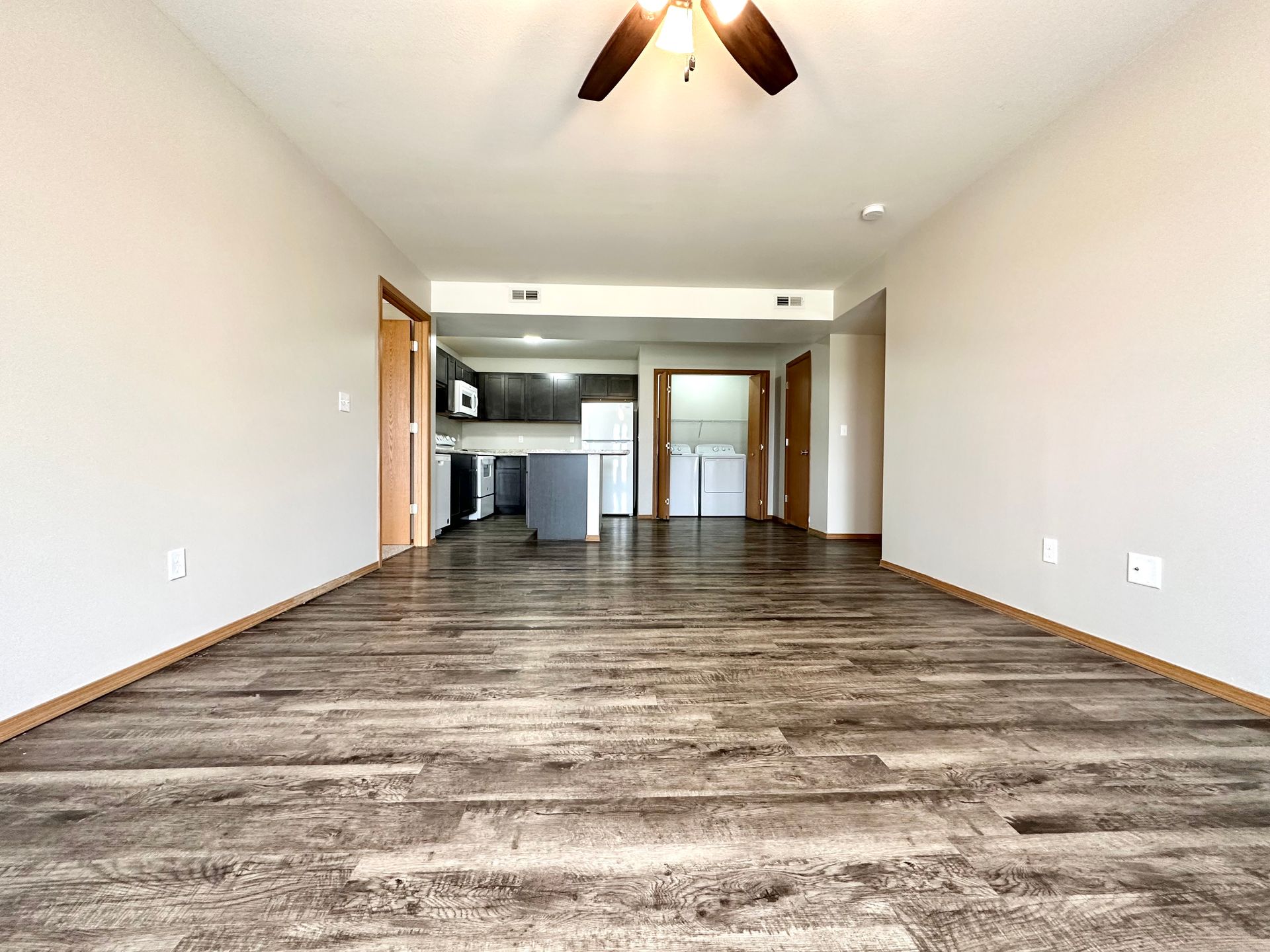 an empty living room with hardwood floors and a ceiling fan .