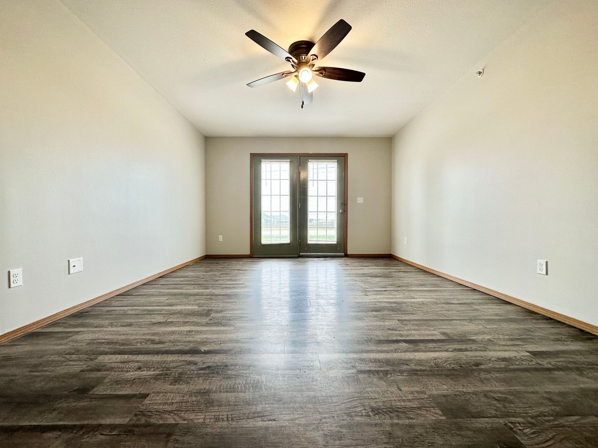an empty room with a ceiling fan and sliding glass doors