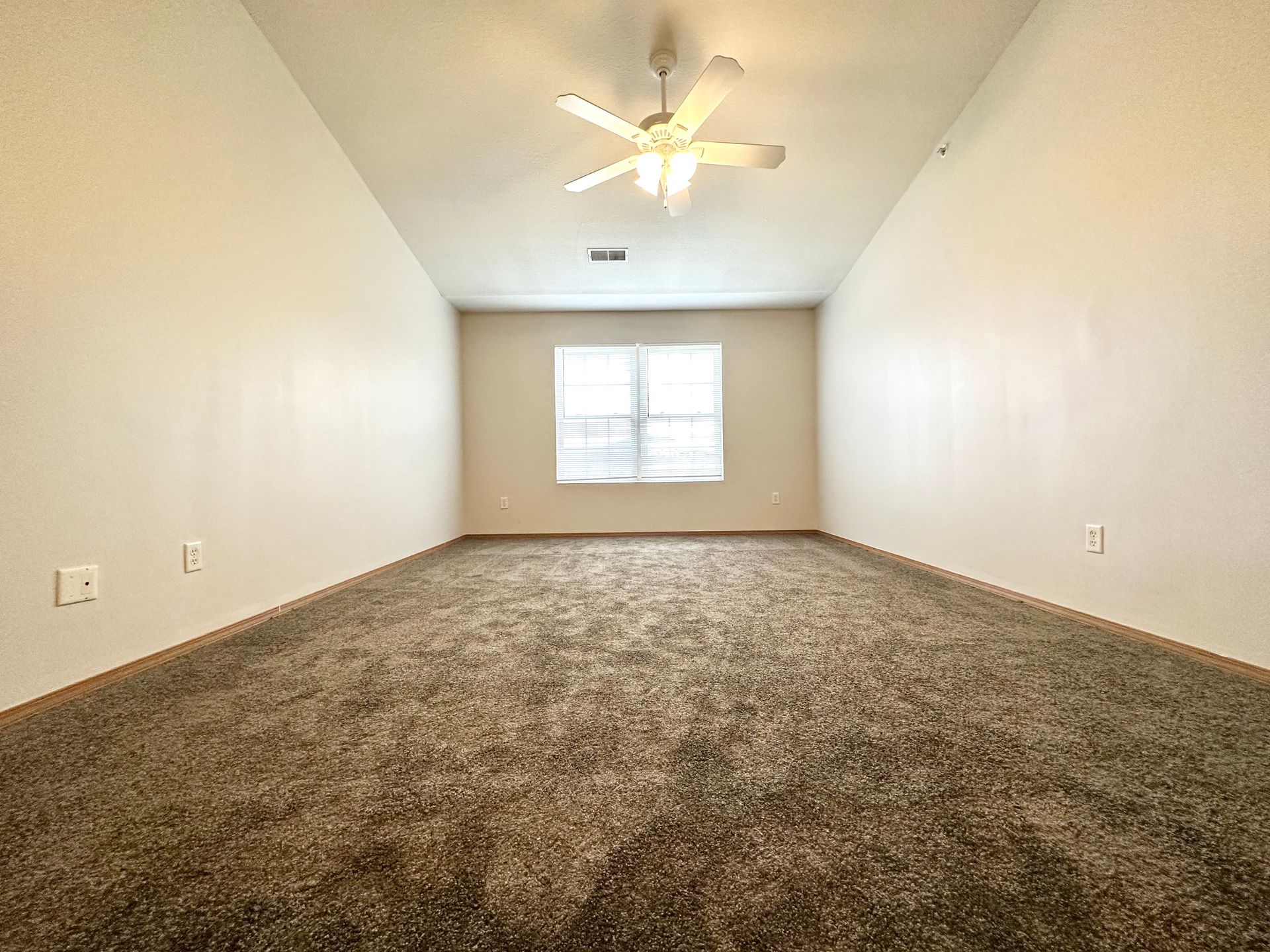an empty room with a ceiling fan and a window .
