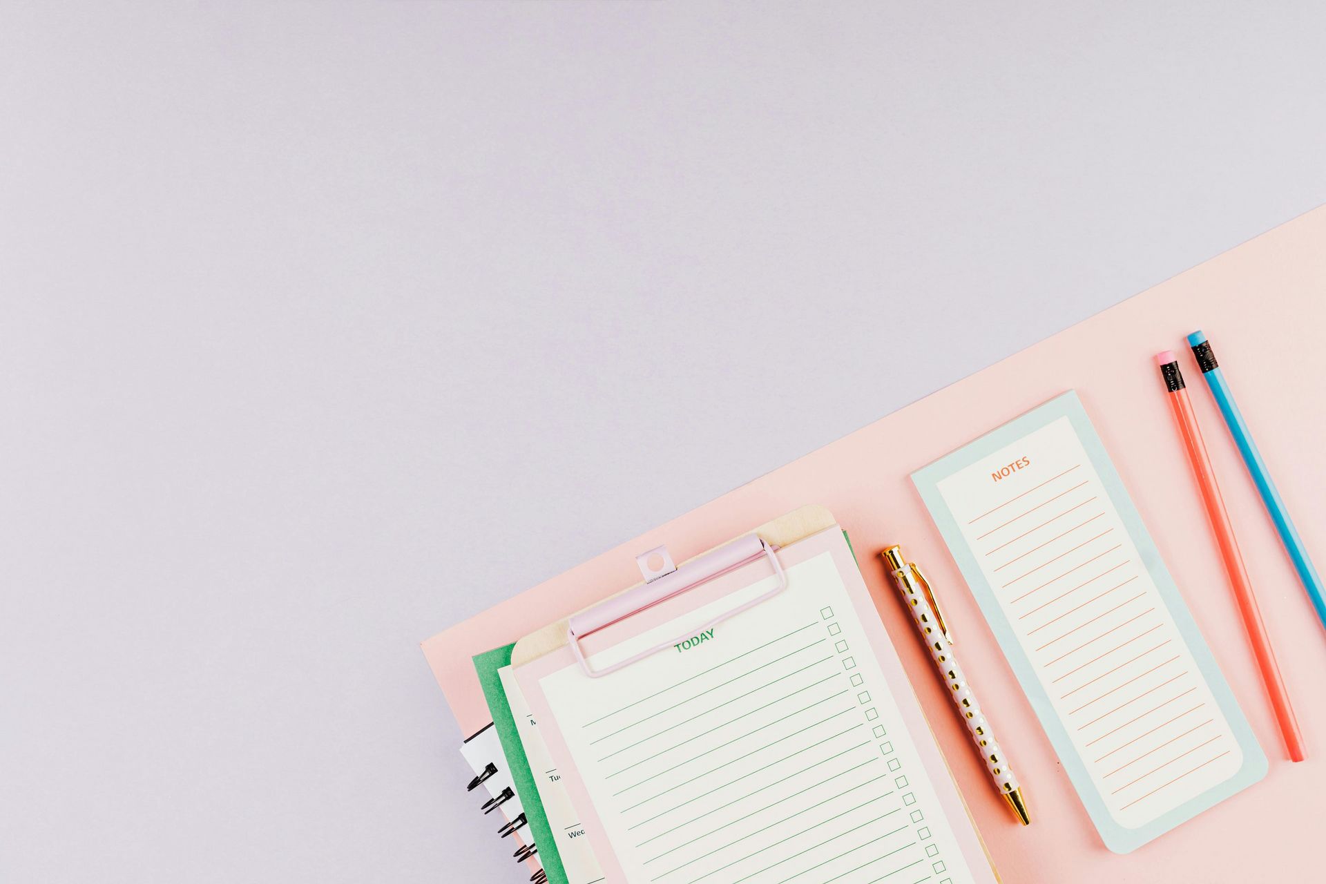Clipboard, papers, pen, pencils on pink and purple background.