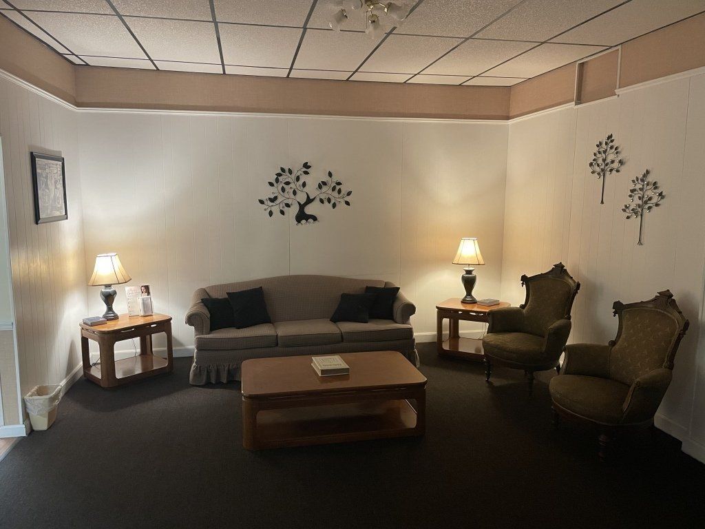 A living room with a couch , chairs , tables and lamps.