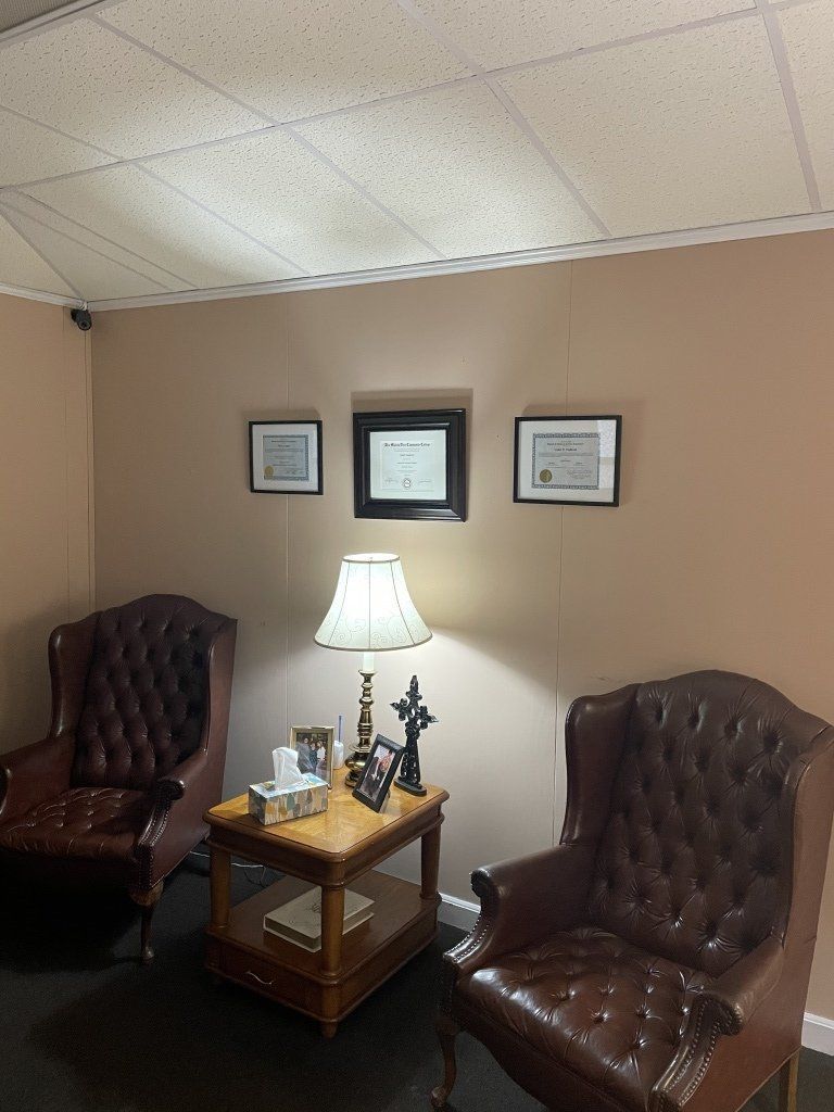 A living room with two chairs , a table and a lamp.