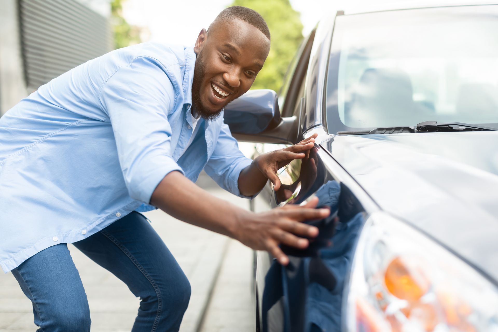 A man is scratching the side of a car.