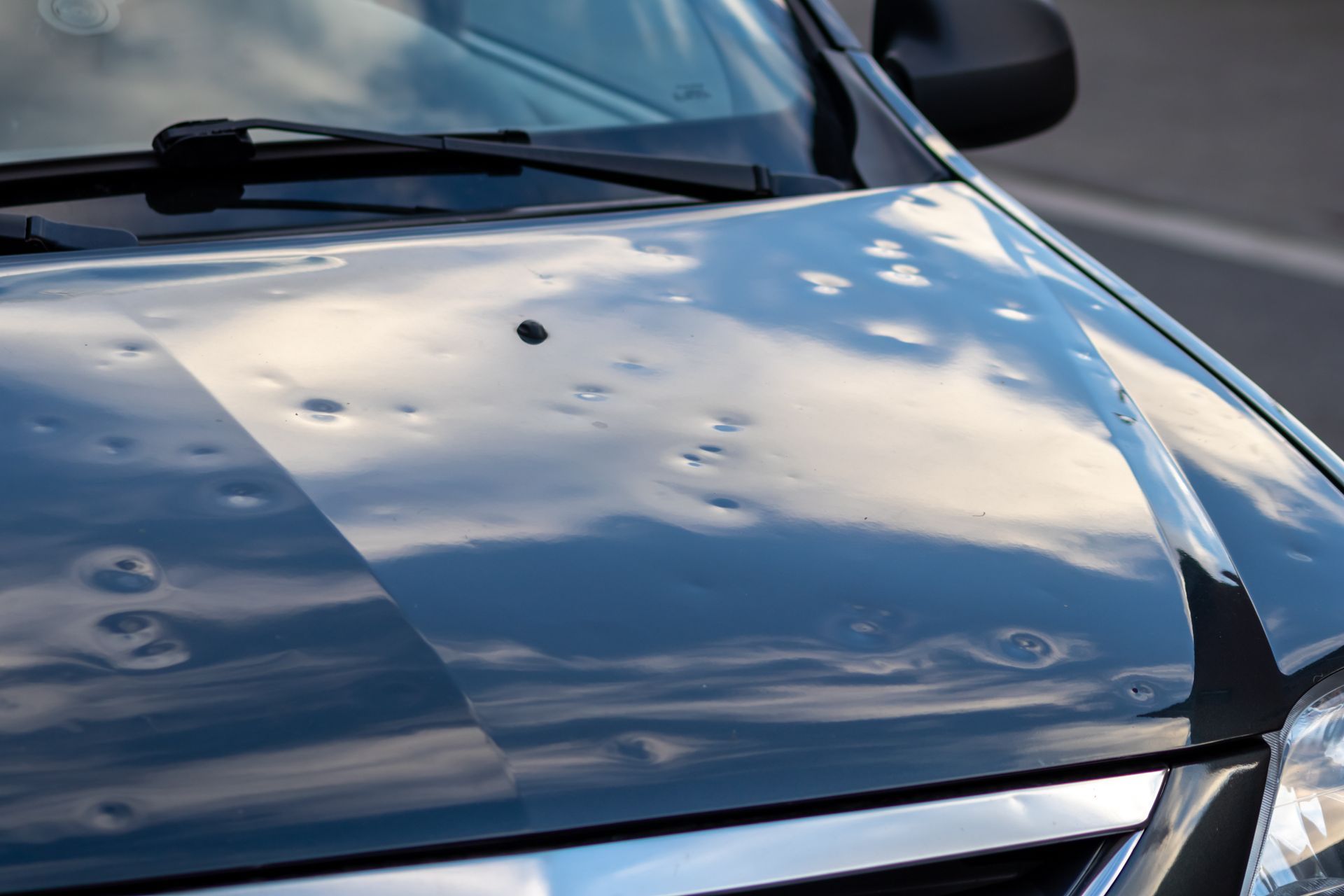 The hood of a car has been damaged by hail.