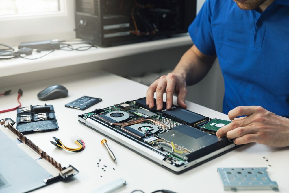 A Man is Working on a Laptop Under the Hood of a Car — Computers NQ in Aitkenvale, QLD