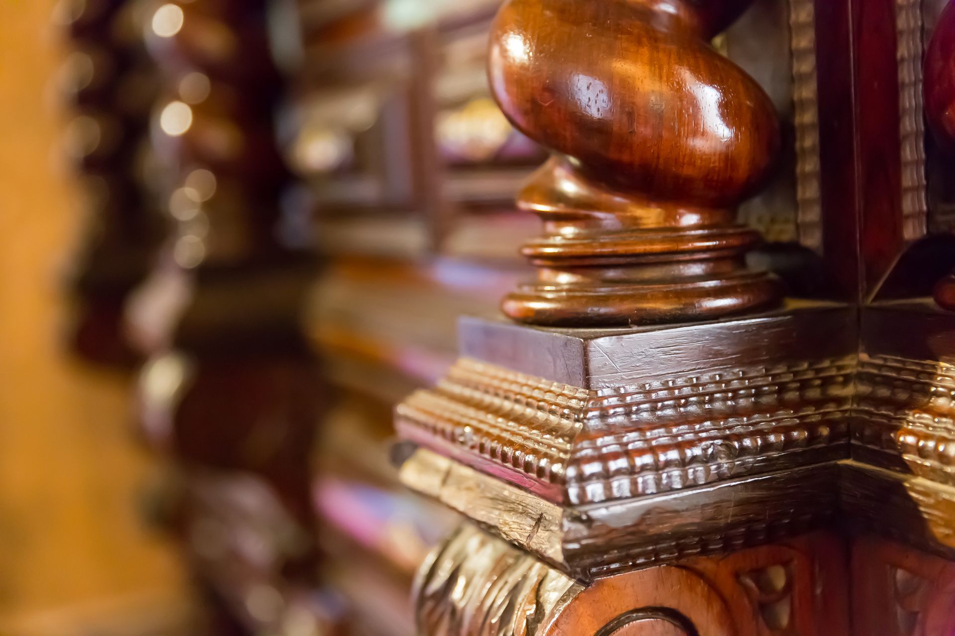 Close-up of a carved wooden furniture piece featuring a spiral column and detailed, ornate decorative molding.