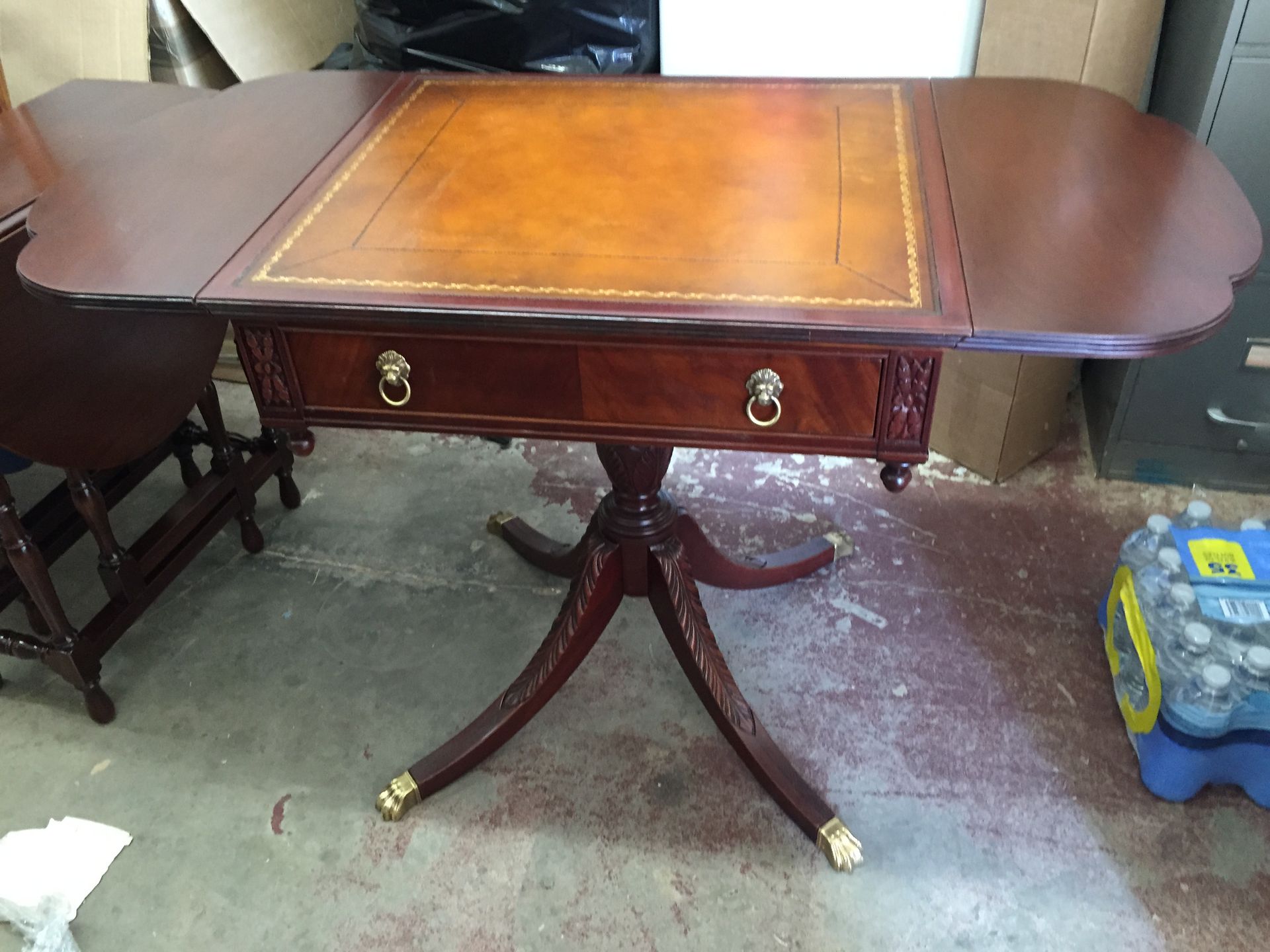 A tall, dark wooden antique hutch with glass doors, open shelves, and four drawers, standing between two sheer curtains.