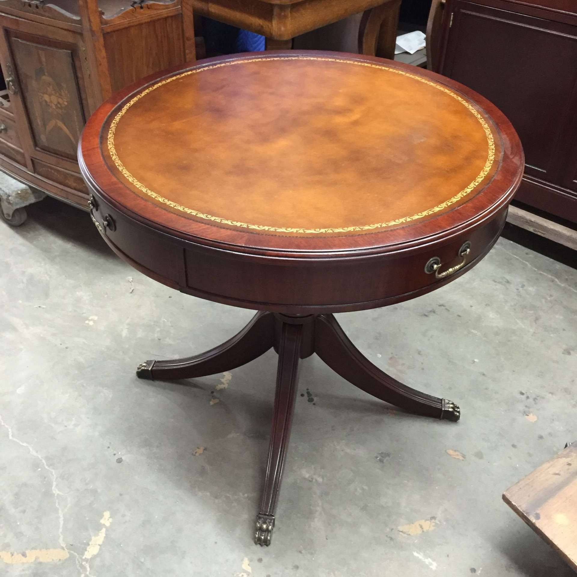 A wooden chest of drawers with five drawers and metal hardware, set against a white wall with vases on top.