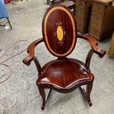 A dark wooden roll-top desk with a lit candle, a notebook, a fan, and a quill pen in a dimly lit, vintage-style study.