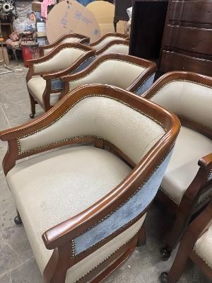 A close-up of a carved wooden furniture piece featuring floral details, a curved top edge, and a distressed finish.