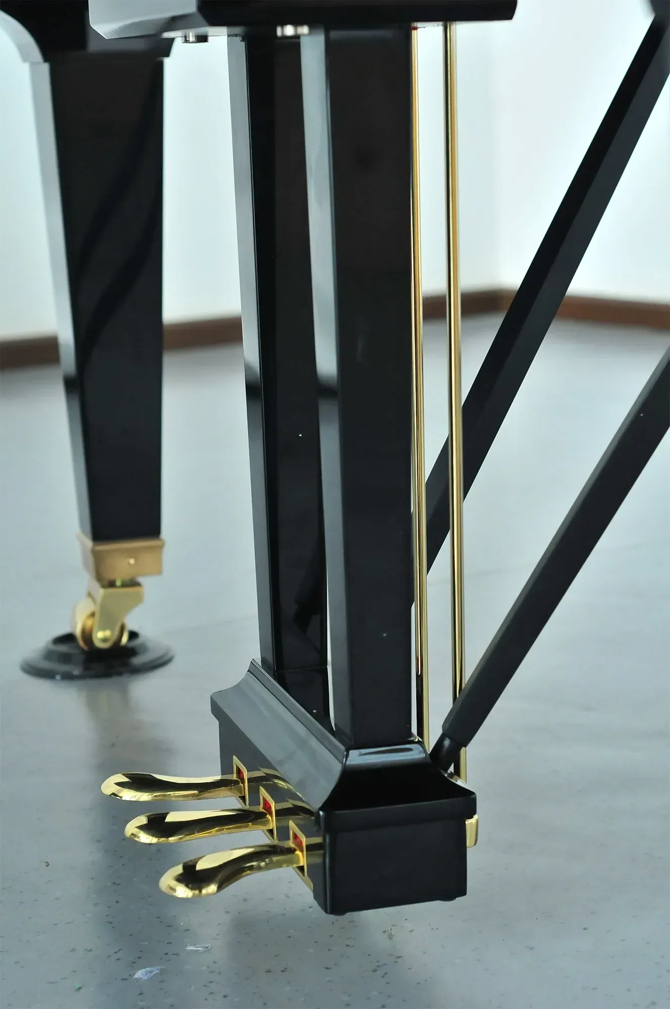 A close up of a black piano with gold pedals