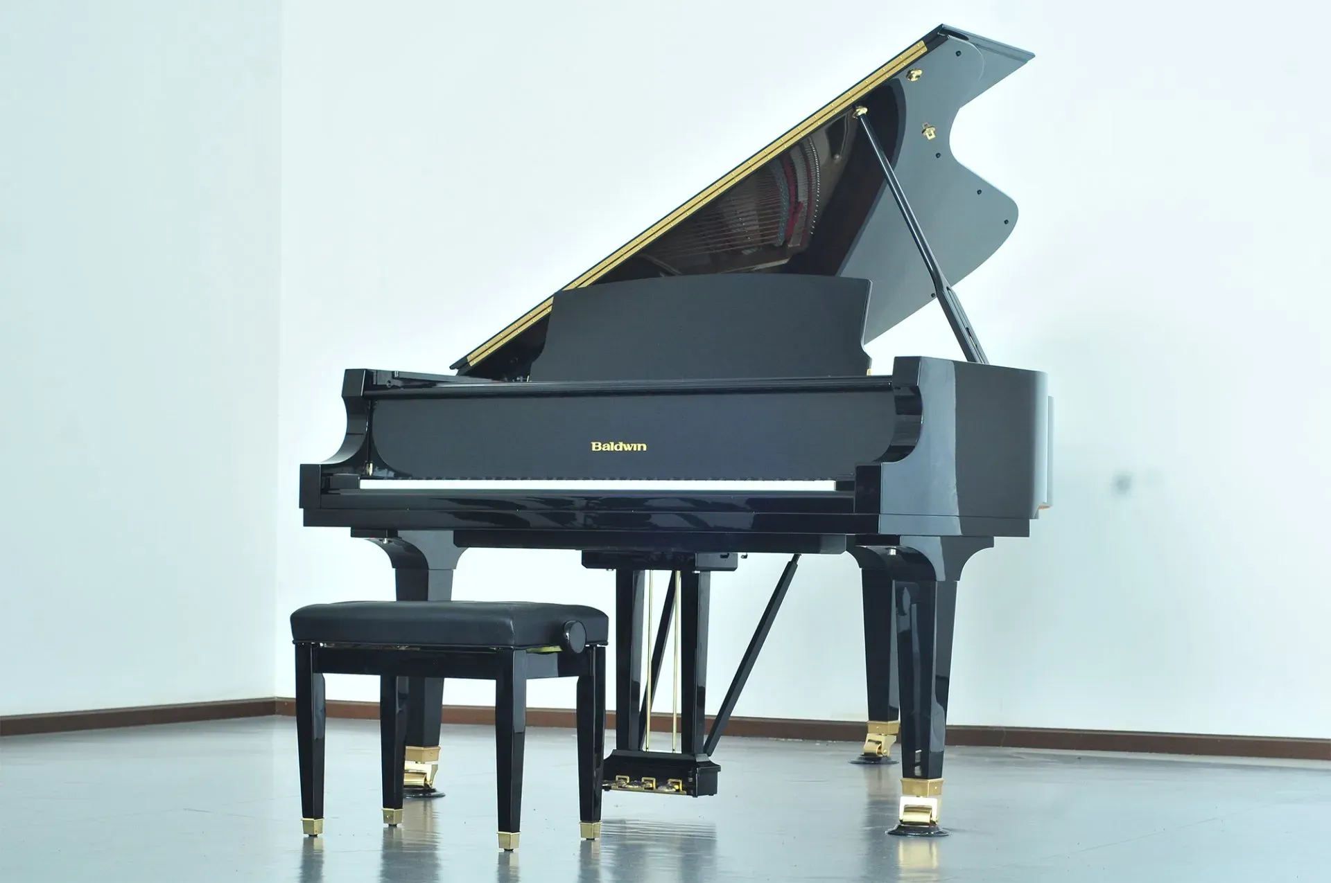 A black grand piano is sitting in a room with a stool next to it.